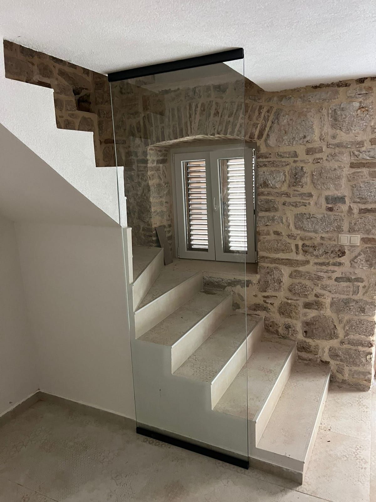 Fixed glass wall beside a staircase and a stone wall
