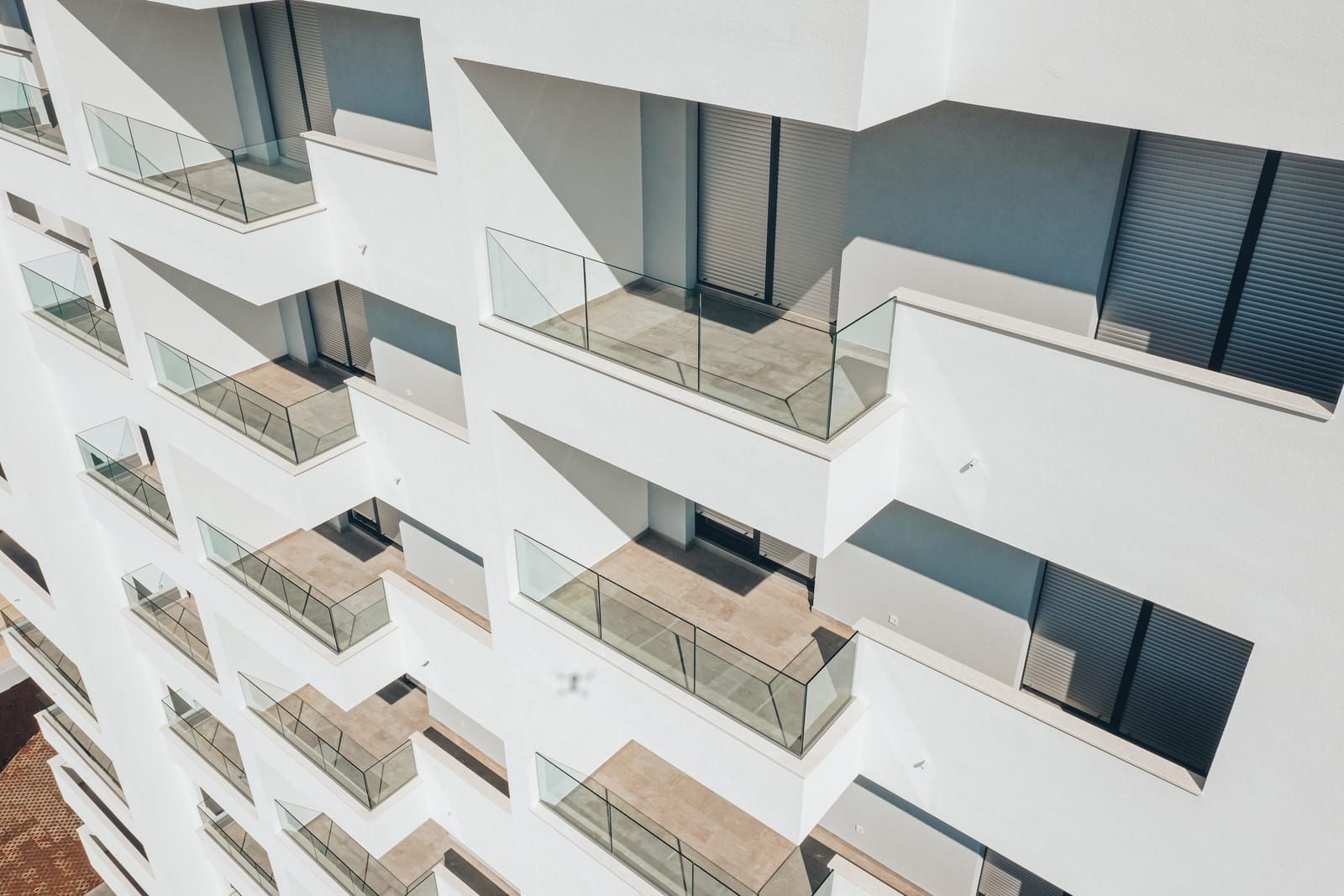 Glass railings on a row of balconies of a white apartment building