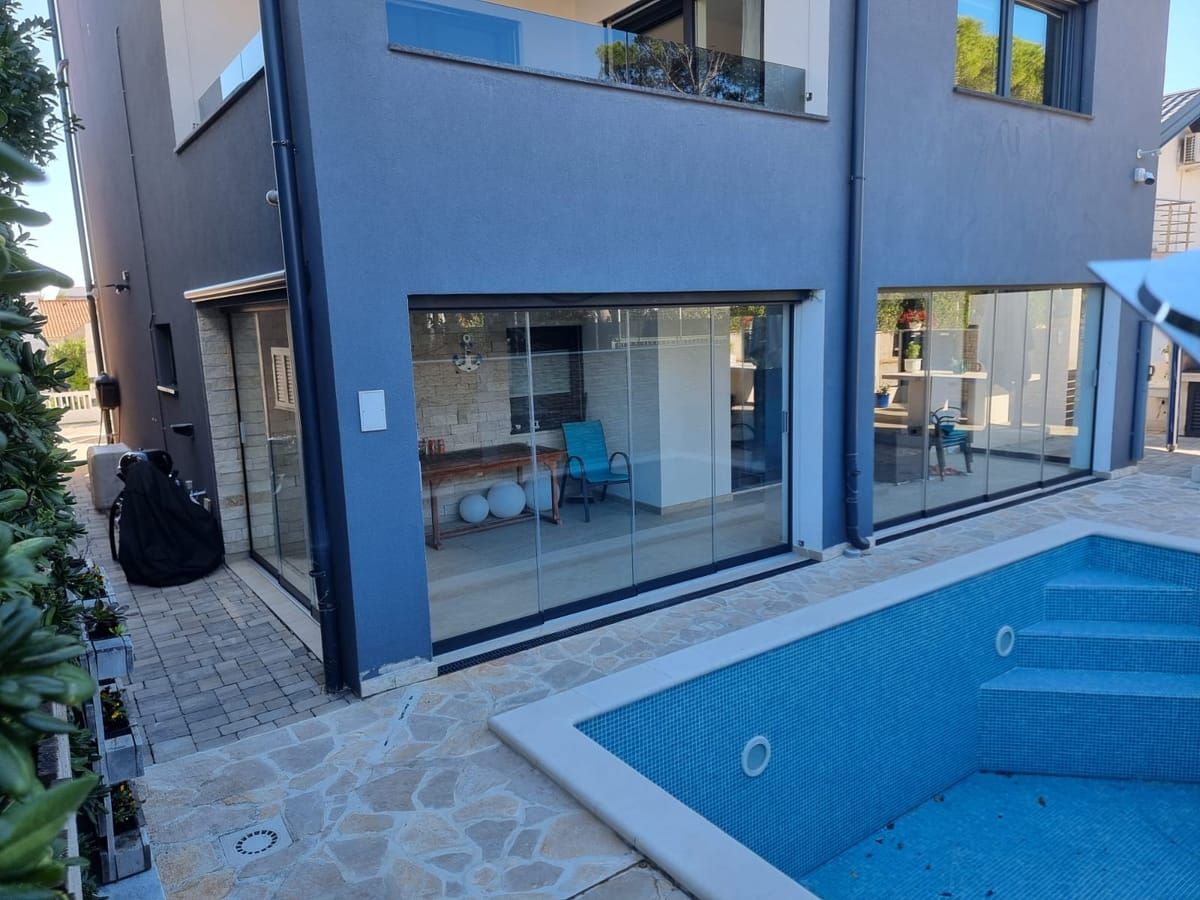 Sliding glass wall of a terrace beside a pool