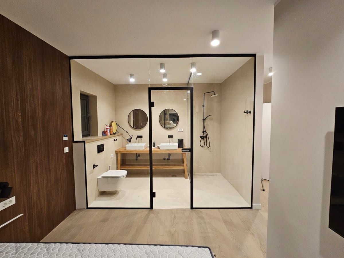 Glass wall with a door separating a bathroom from a bedroom